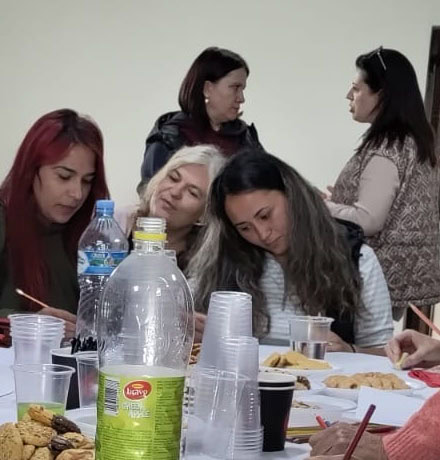 Vrouwen genieten van een bijeenkomst met eten en drankjes bij Dorcas, focus op sociale connectie en community.