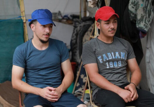Twee jonge mannen zitten samen in een tent,