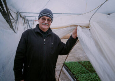 Zachtlopende man in kas met jonge plantjes onder een kasdoek.