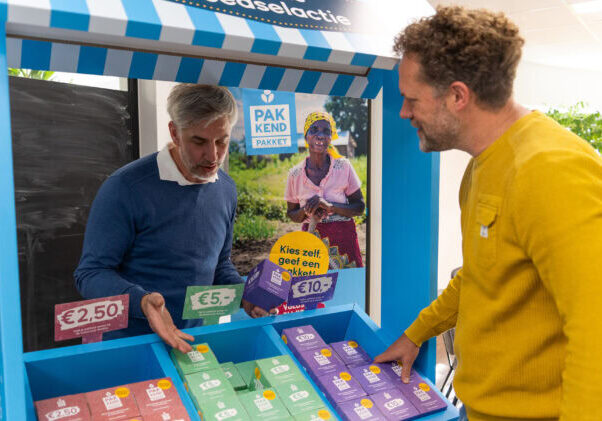 Dames en heren kopen gezonde producten bij een steunt Kiosk voor ontwikkelingshulp.